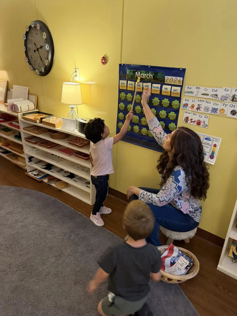 Teacher helping a child during a classroom calendar lesson