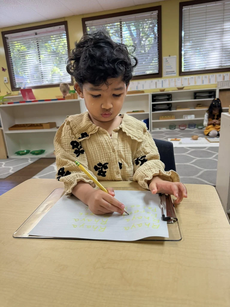 Child practicing handwriting with a pencil and clipboard in the classroom