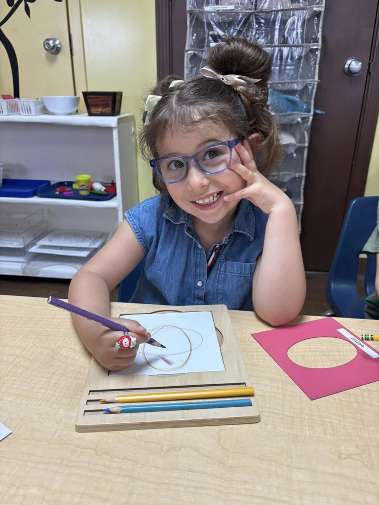 Child tracing shapes on paper during a Montessori classroom activity