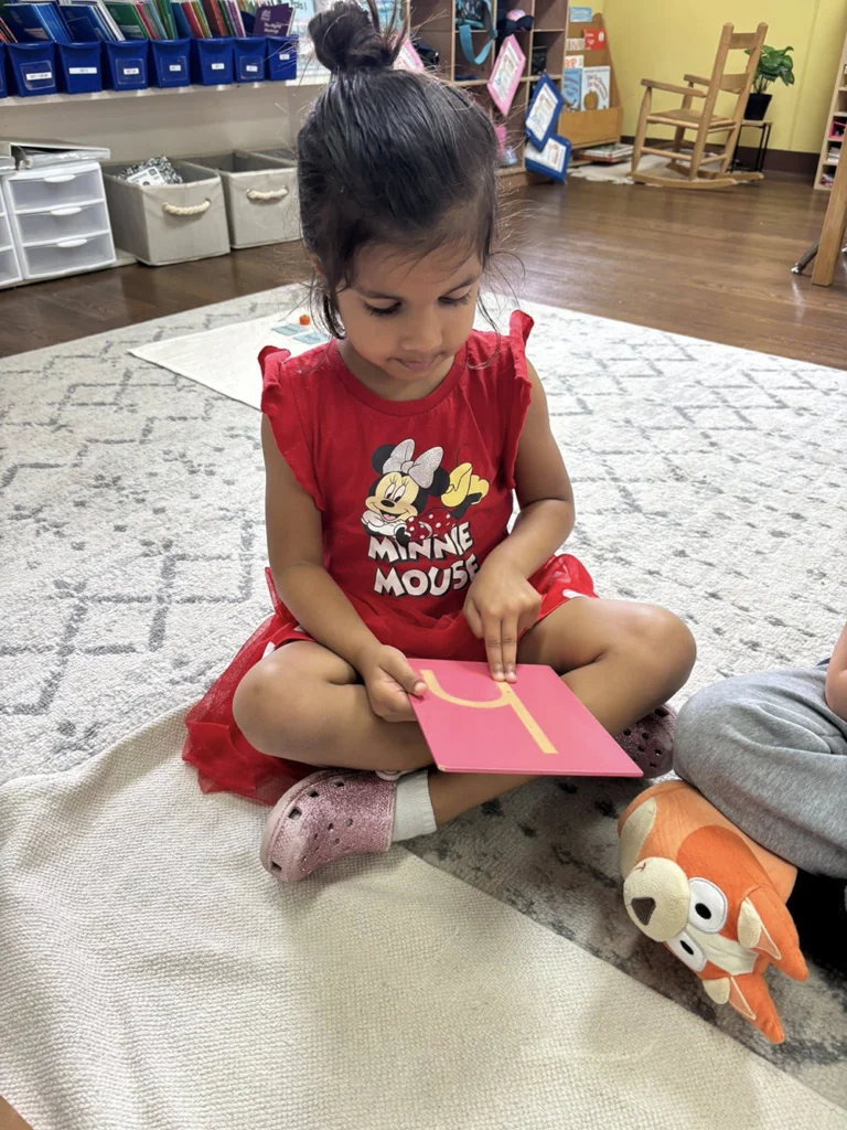 Child tracing a letter during a Montessori language lesson