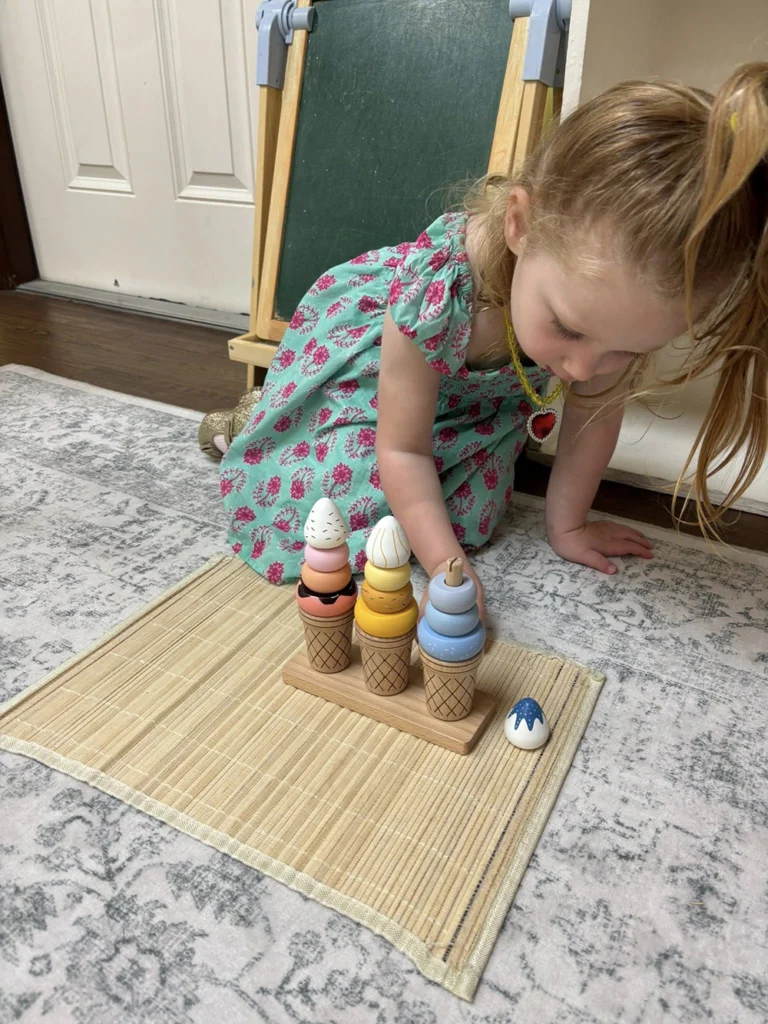 Child stacking wooden pieces during a fine motor classroom activity