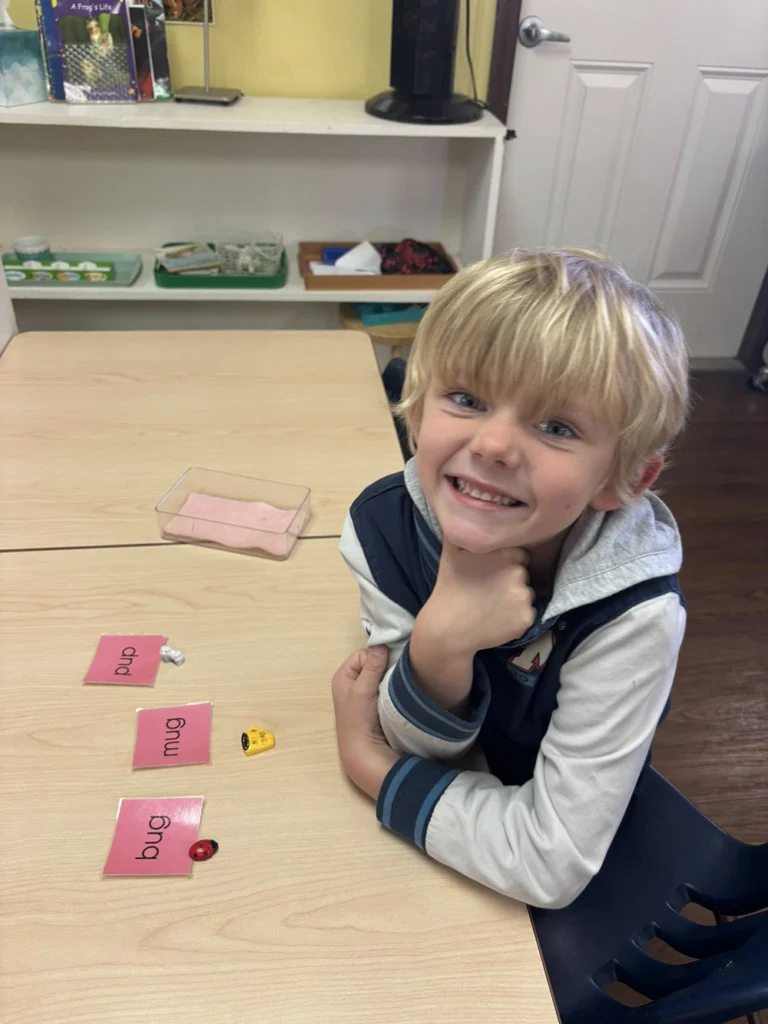 Child matching word cards with small objects at a classroom table