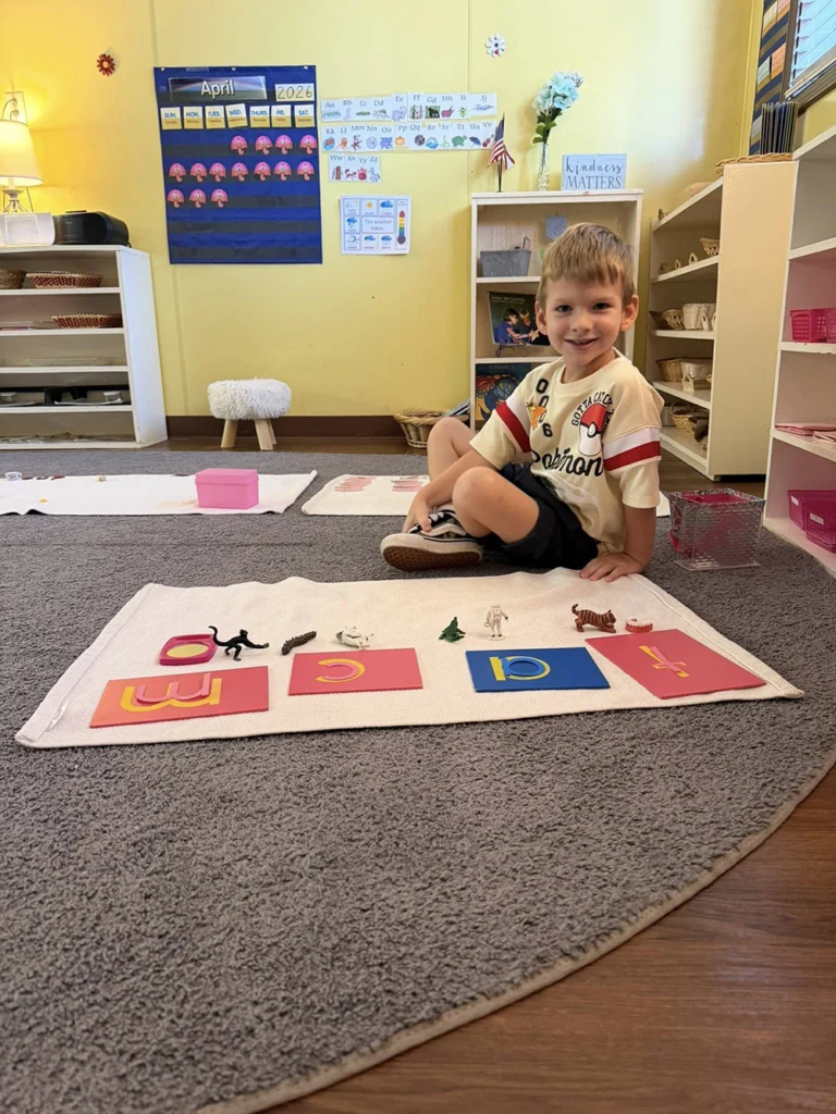 Child matching letter sound cards with small objects on a classroom mat