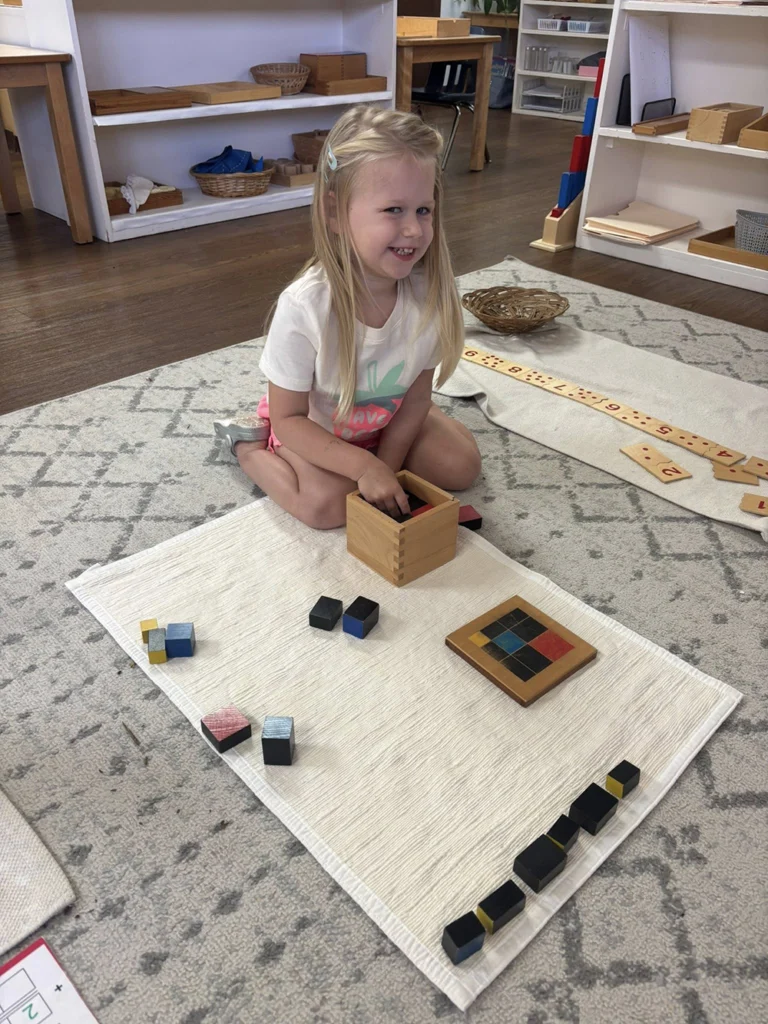Child working with Montessori color tablets on a classroom mat