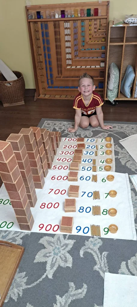 Child working with Montessori decimal system materials on a classroom rug
