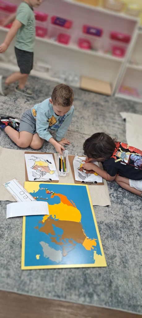 Children working with a Montessori map and geography materials on the floor
