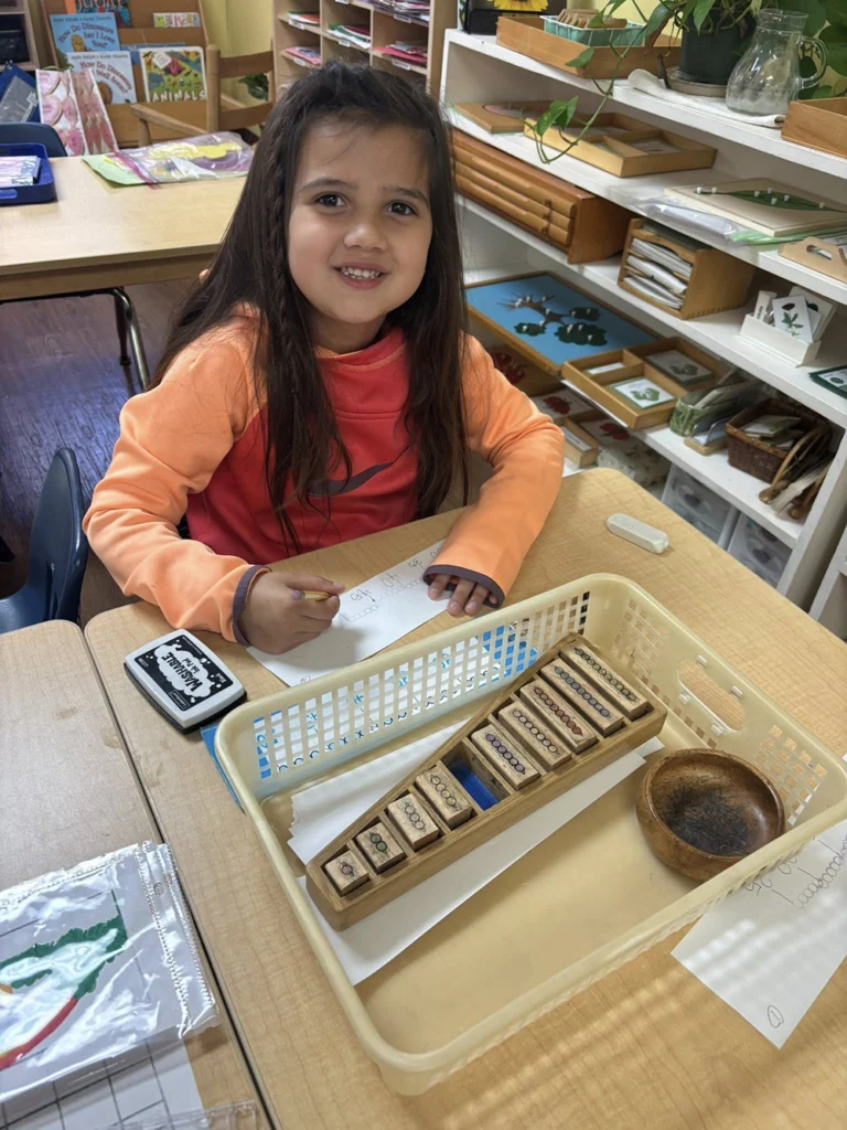 Child working with Montessori math stamp game materials at a table