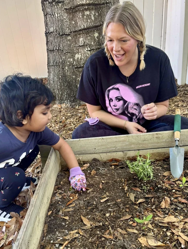 Teacher helping a child plant in the school garden