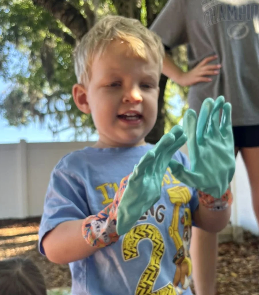 Child in a Montessori school with vibrant green paint on his hands for a craft.