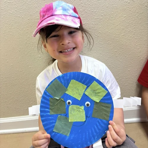 Young student holding a paper plate craft during a Montessori classroom activity